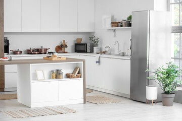 Interior of stylish kitchen with modern fridge and island table