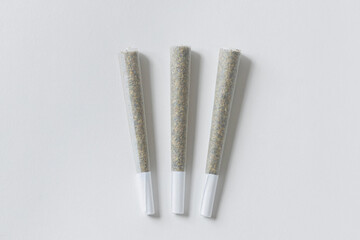Three Marijuana joints on white surface