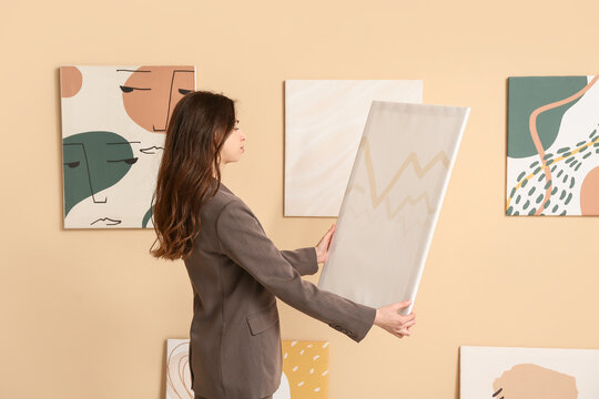 Young woman with painting at art gallery exhibition