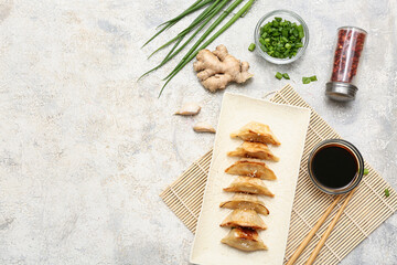 Plate of fried Japanese gyoza with bowl of soy sauce and green onion on white background