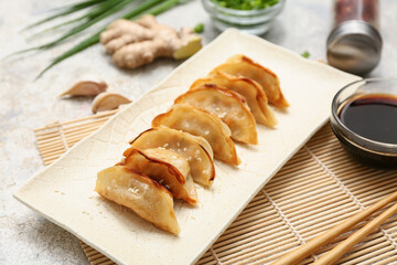 Plate with fried Japanese gyoza and bowl of soy sauce on white background, closeup