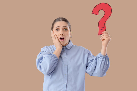 Puzzled woman holding question mark on beige background