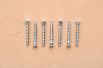 Row of screws on beige background
