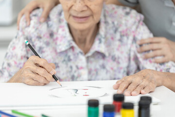 Happy smiling old senior woman drawing on paper,joyful,enjoying,Drawing and coloring activity for the elderly,creative skill and imagination,creativity and relaxation,reduce stress,boredom and anxiety