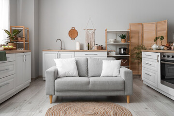 Interior of light kitchen with counters, shelf units and sofa