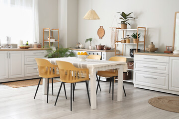 Interior of light kitchen with counters, shelf units and dining table