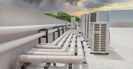 Air conditioning (HVAC) on the roof of an industrial building with blue sky and clouds.