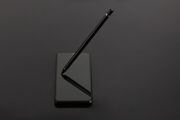 Stylus for drawing on capacitive screens. The stylus lies on the smartphone screen on a black background.