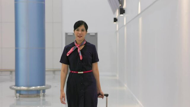 Walking in airport. Cabin crew, air hostess working in airplane. Service mind. Asian stewardess with suitcase at modern airport terminal. flight attendant