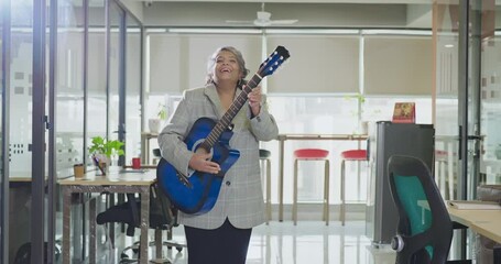 Indian Asian happy senior gen x business woman play guitar singing song indoor job place excited cute old silly crazy lady staff worker dancing enjoy day break time have fun joyful joy work office