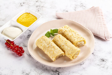 Homemade stuffed pancakes with honey and cream sour