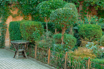 Obraz premium garden day spring blossom season floral concept yard pavement street small table decorative objects near flower bed with green foliage plants