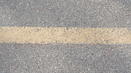 Fototapeta premium Close-Up of a Weathered Yellow Line on Asphalt Road Surface