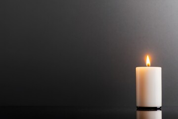 Single lit candle on dark background.