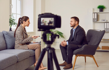 Woman reporter conducting an interview with a guest, recording on a video camera for a TV show....