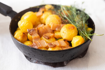 Young potatoes with pork belly fried in frying pan