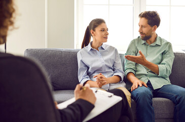 Consultation with family psychologist. Young man and wife are sitting on couch and talking to each...