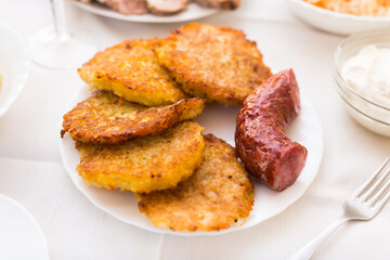 Potato pancakes with fried sausage on white plate