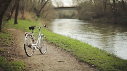 Fototapeta premium Vintage bicycle parked by a tranquil river on a dirt path.