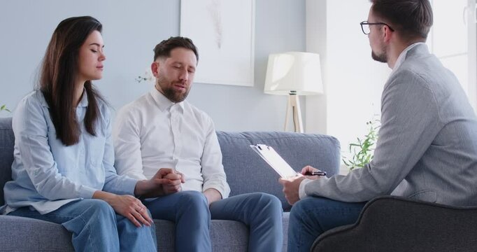 Supportive loving couple sitting at couch talking with family relationships expert trying to save marriage, reproductologist session, husband, wife consult with psychologist about health, surrogacy