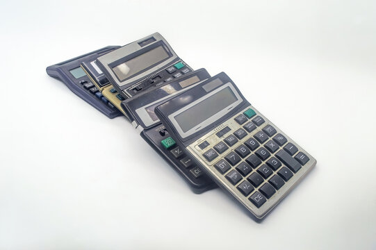 A pile of old calculators symbolizes inflation, representing outdated financial tools and the increasing cost of living