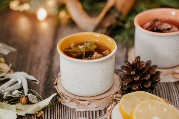 Cozy winter vibes with herbal tea, dried citrus slices, and seasonal decor – Christmas lights and fir tree branches