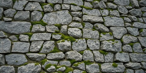 Obraz premium A textured grey stone wall with patches of vibrant green moss growing between the irregularly shaped rocks.
