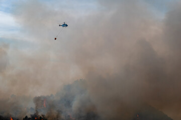 Helicóptero no combatendo a incêndio florestal em meio a densas nuvens de fumaça