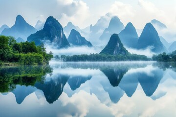Serene Landscape of Majestic Mountains Reflected in Tranquil Lake with Misty Atmosphere and Lush Greenery Beneath a Soft Blue Sky