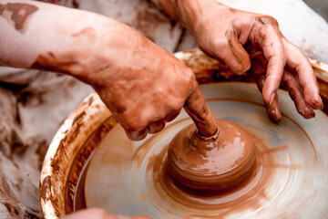 Potter sculpts mug from clay, close up dirty hands create vase on ceramist wheel