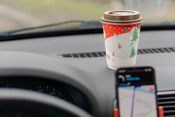 Background with paper coffee cup and car interior with phone navigation