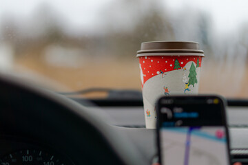 Background with paper coffee cup and car interior with phone navigation