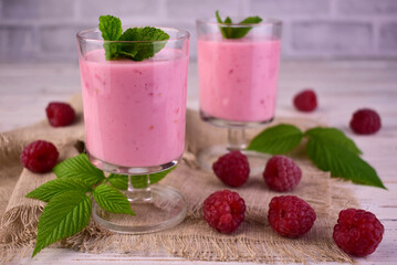 Raspberry smoothie in glasses on a white wooden background.
