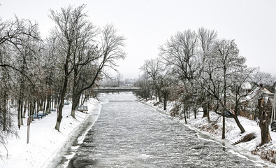 Snow-covered riverbank lined with trees in a winter landscape