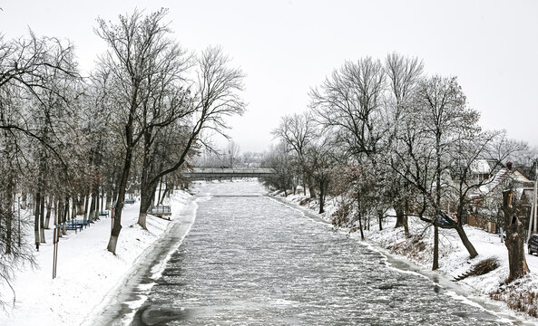 Snow-covered riverbank lined with trees in a winter landscape