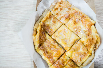 Roti with egg and sweetened condensed milk, cut into square pieces, placed on white paper.