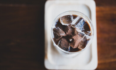 Top view of a glass of ice Mocha coffee with topping that sprinkle chocolate powder over the surface in wood table