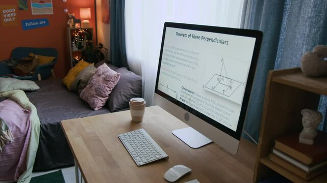 Statement and proof of geometric theorem displayed on computer monitor on wooden desk with wireless keyboard and reusable coffee cup next to bed in students room