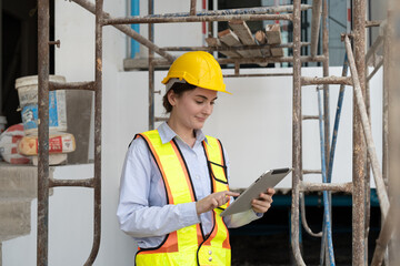 Civil engineer woman in vests and helmet safety holding tablet working at construction site. Female...