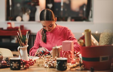 A young woman immersed in the joy of Christmas crafting, surrounded by vibrant decorations and warm...