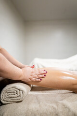 Vertical photo of a professional's hands massaging a man's legs inside a spa.Concept of leg massages for adult men.