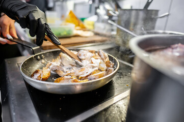 A chef in gloves stir-fries sliced mushrooms in a pan over a hot stovetop, showcasing a bustling kitchen environment with steam rising from pots. Ideal for culinary and restaurant themes.