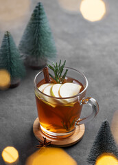 Homemade apple punch with fresh apples, cinnamon and rosemary in a cup on a dark background