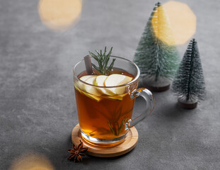 Apple punch or sider with fresh apples, cinnamon and rosemary in a cup on a dark background