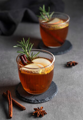 Homemade apple punch with fresh apples, cinnamon and rosemary in a two cups on a dark background