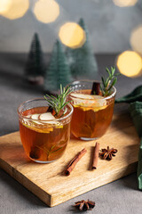 Homemade apple punch with fresh apples, cinnamon and rosemary in a two cups on a wooden board