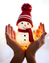tiny cute snowman with glowing light in human hands on the white isolated background; new year, greeting and love