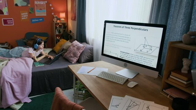 Geometric theorem displayed on computer monitor and study materials left on wooden desk in room of teenage girl with disability lying on bed with laptop