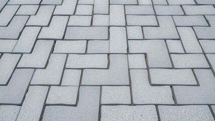 A Detailed Close-Up View of a Herringbone Pattern Pavement Consisting of Light Grey Rectangular Paving Stones