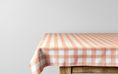 Empty wooden table with orange gingham tablecloth against a white wall.